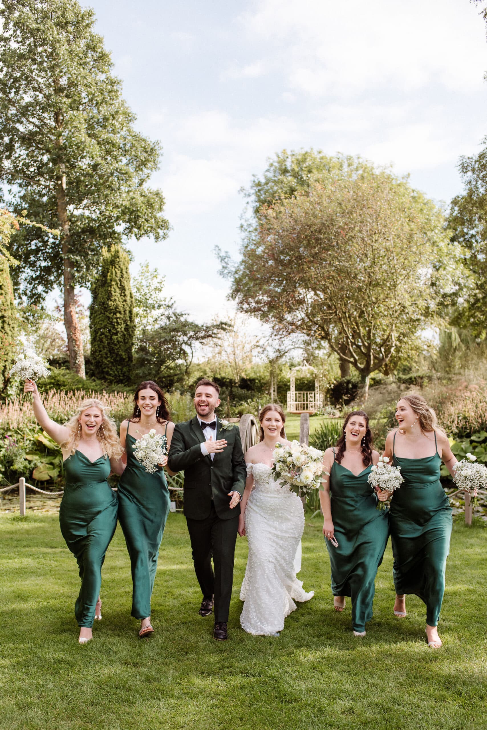 Bride and her ' I do' crew walking up the green lawns with the Summerhouse behind them country house wedding venue