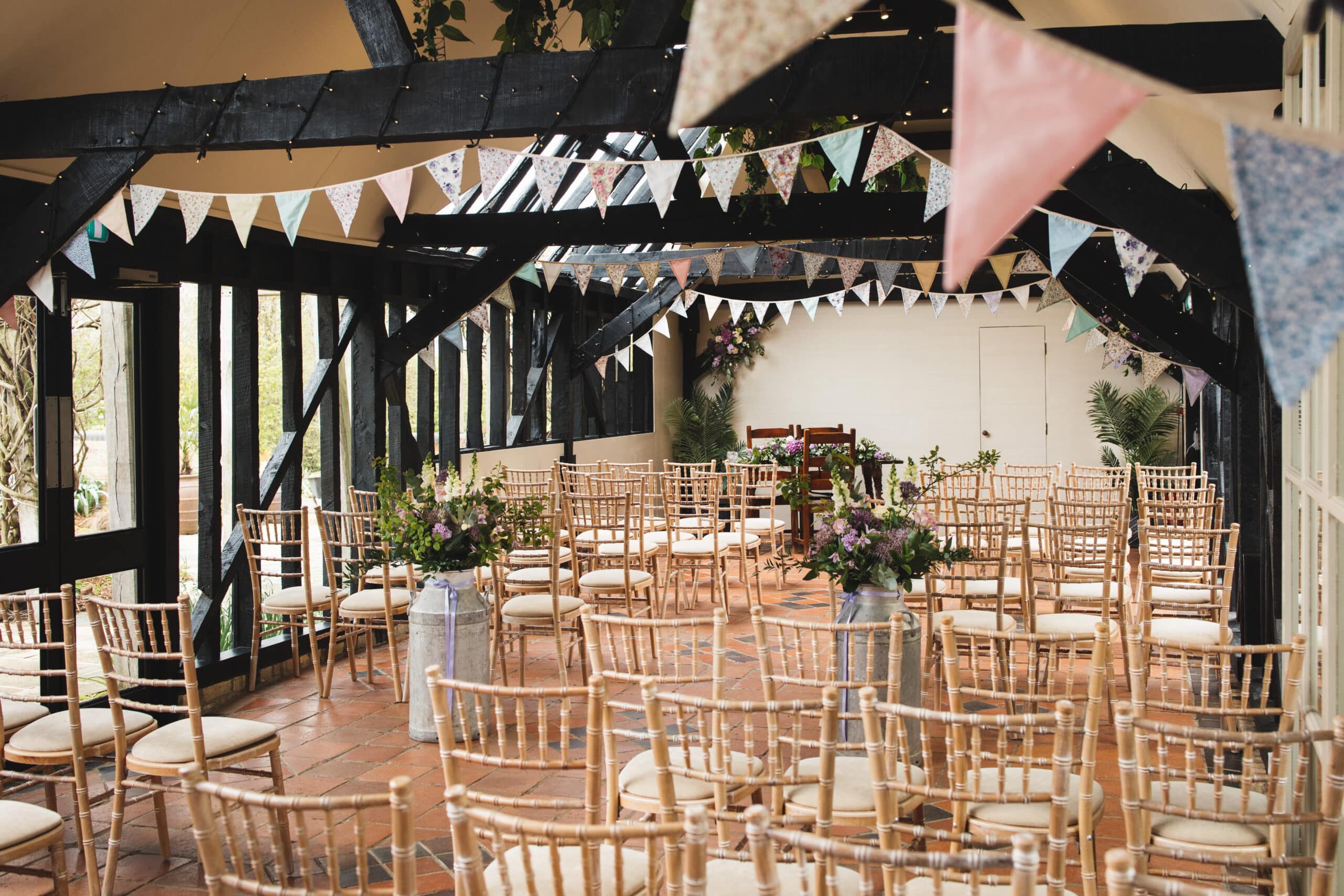 The Old Dairy all set with beautiful colourful bunting and Spring flowers in milk churns at barn style wedding venue in Hertfordshire
