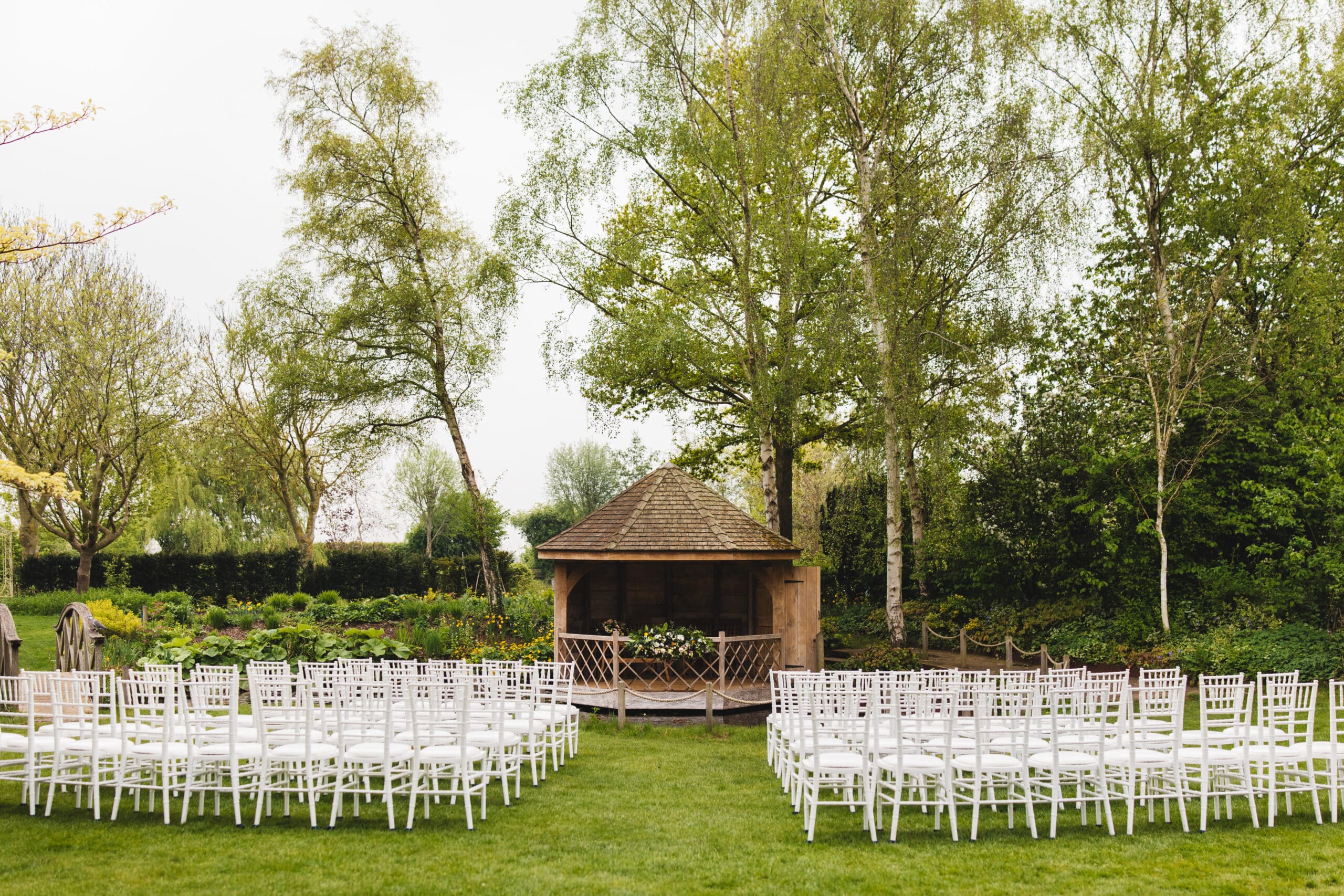 The Summerhouse all set for beautiful outdoor ceremony with Spring blossoms behind at outdoor garden wedding venue