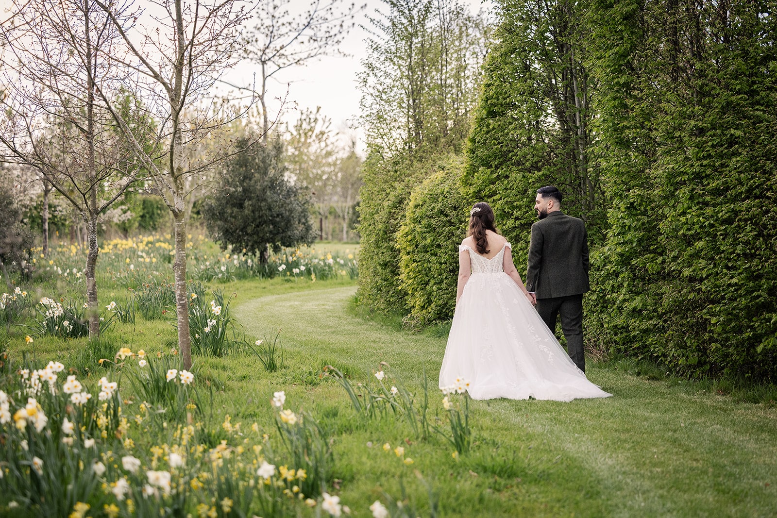 Bride and Groom having a stroll through the Spring-filled meadows at countryside wedding venue