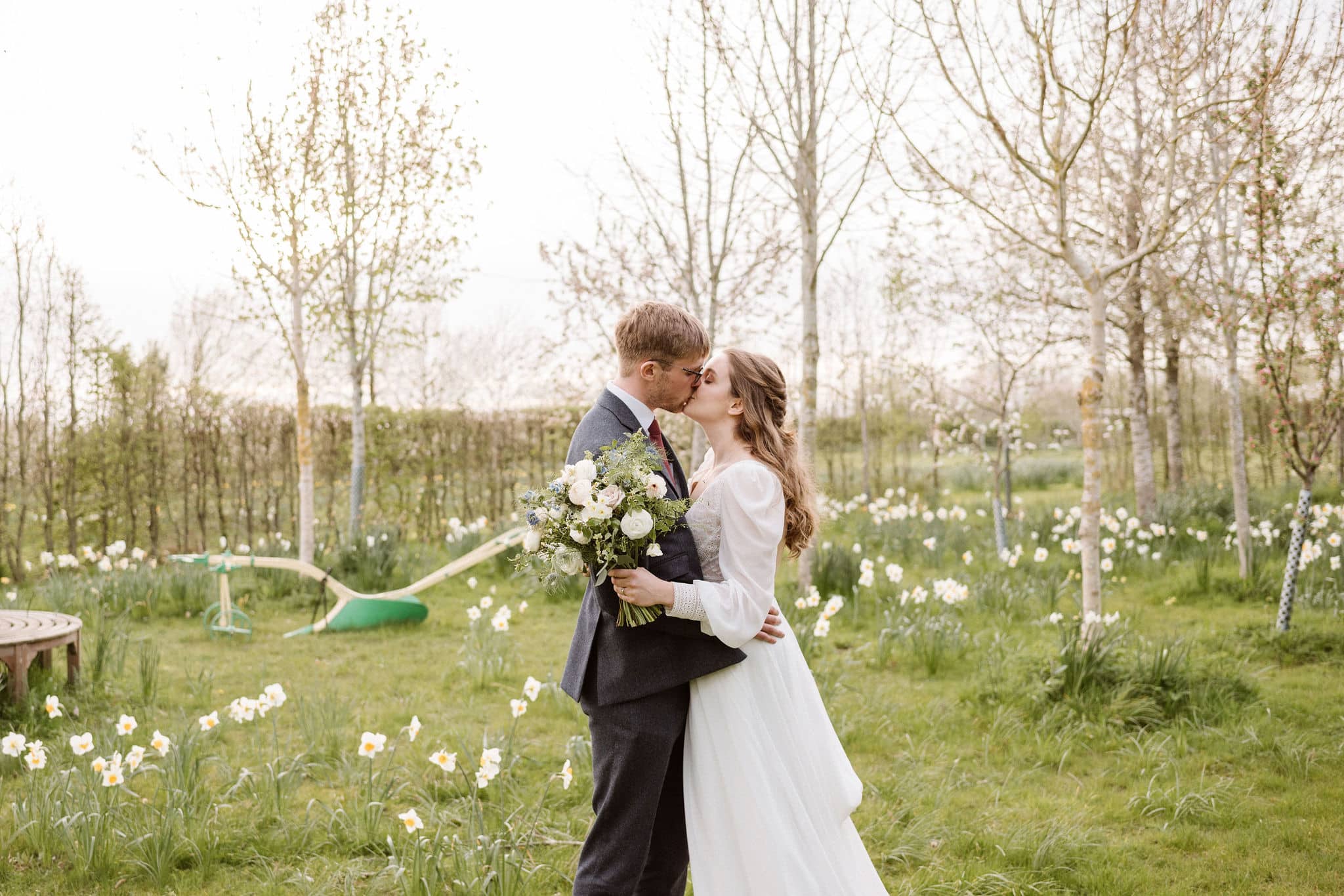 Bride ang Groom having a kiss in the arboretum adorned with Spring blossoms at garden wedding venue in Cambridshire