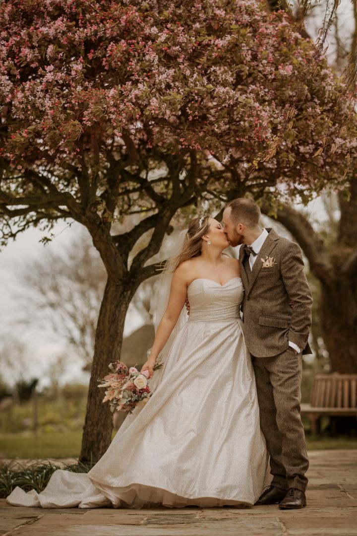 Bride and Groom having a romantic kiss in front of the blossoms on the Garden Terrace in Spring