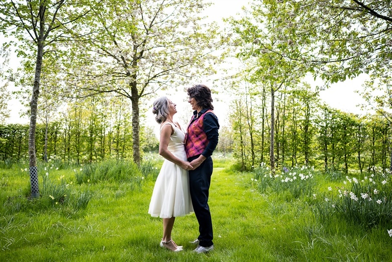 Bride and Bride standing in the Arboretum with Spring blossoms and daffodils at outdoor garden wedding venue