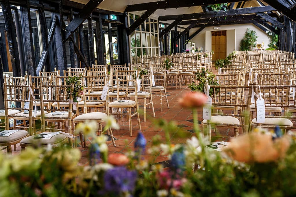 Spring Wedding Ceremony set up at barn wedding venue with ceremony chairs and pretty flowers in the foreground
