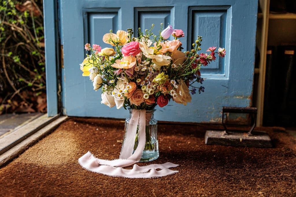 Spring flowers at country house wedding venue in front of blue open door