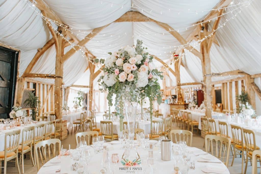 Rustic Barm set for wedding meal with beautiful flowers and fairy lights
