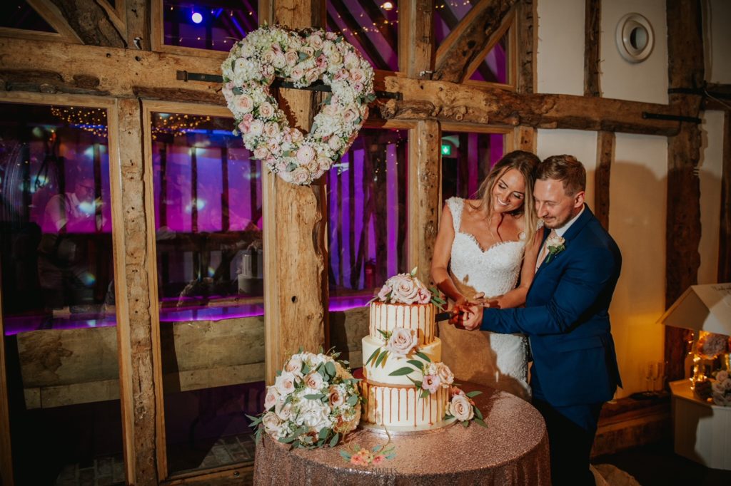 Bride and Groom cut their wedding cake at rustic barn wedding venue