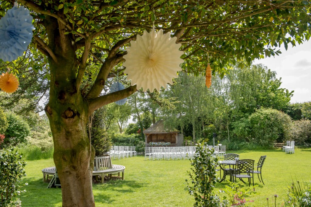 Garden in sunshine with view from tree with colourful paper pinwheel decorations