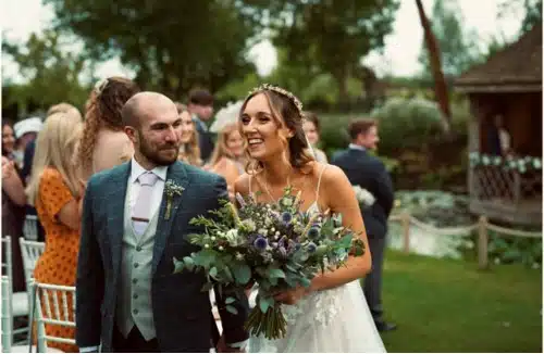 Bride and Groom walking down the aisle after garden ceremony bride holding a beautiful bouquet