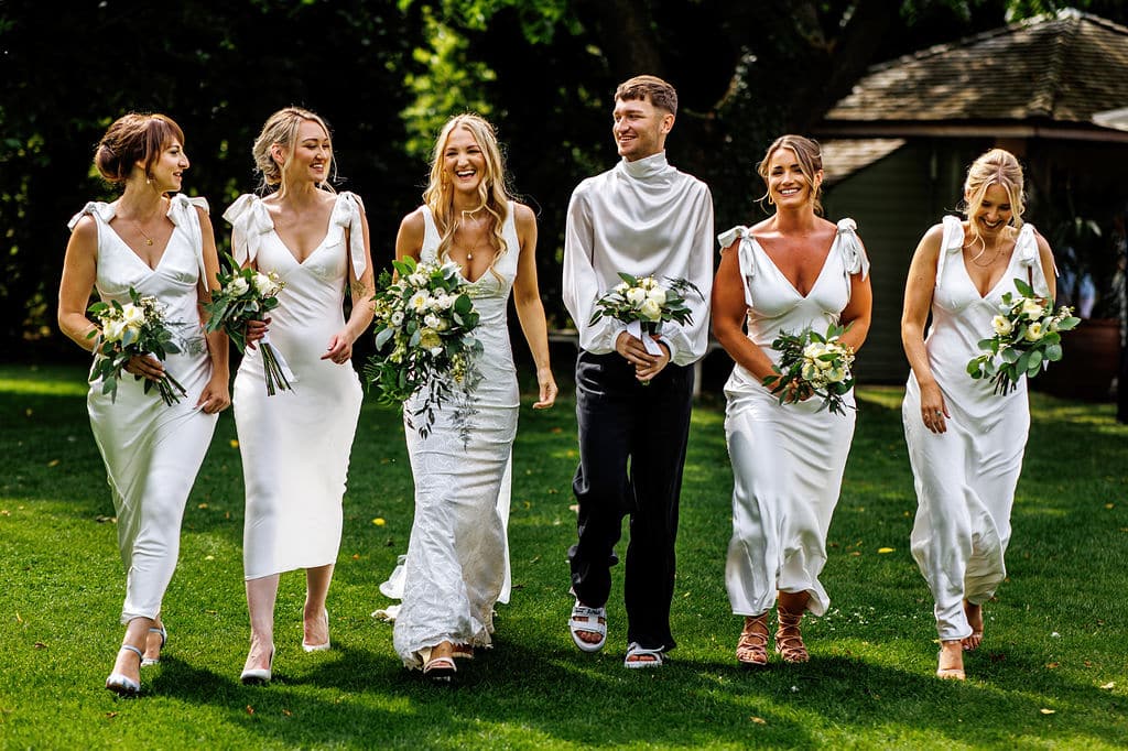 Bride and Bridesmaids and Bridesman with bouquets at garden wedding venue