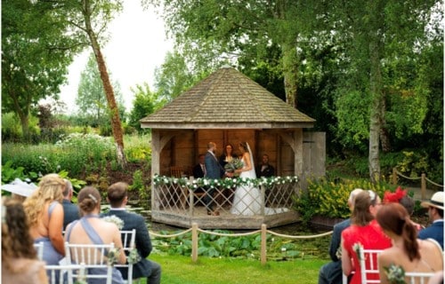 Wedding ceremony in garden summerhouse as guests look on