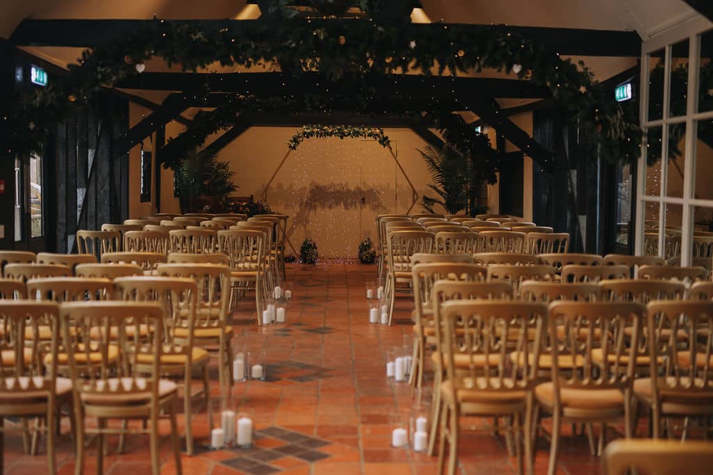 Rustic barn with black beams set for ceremony with gold chairs