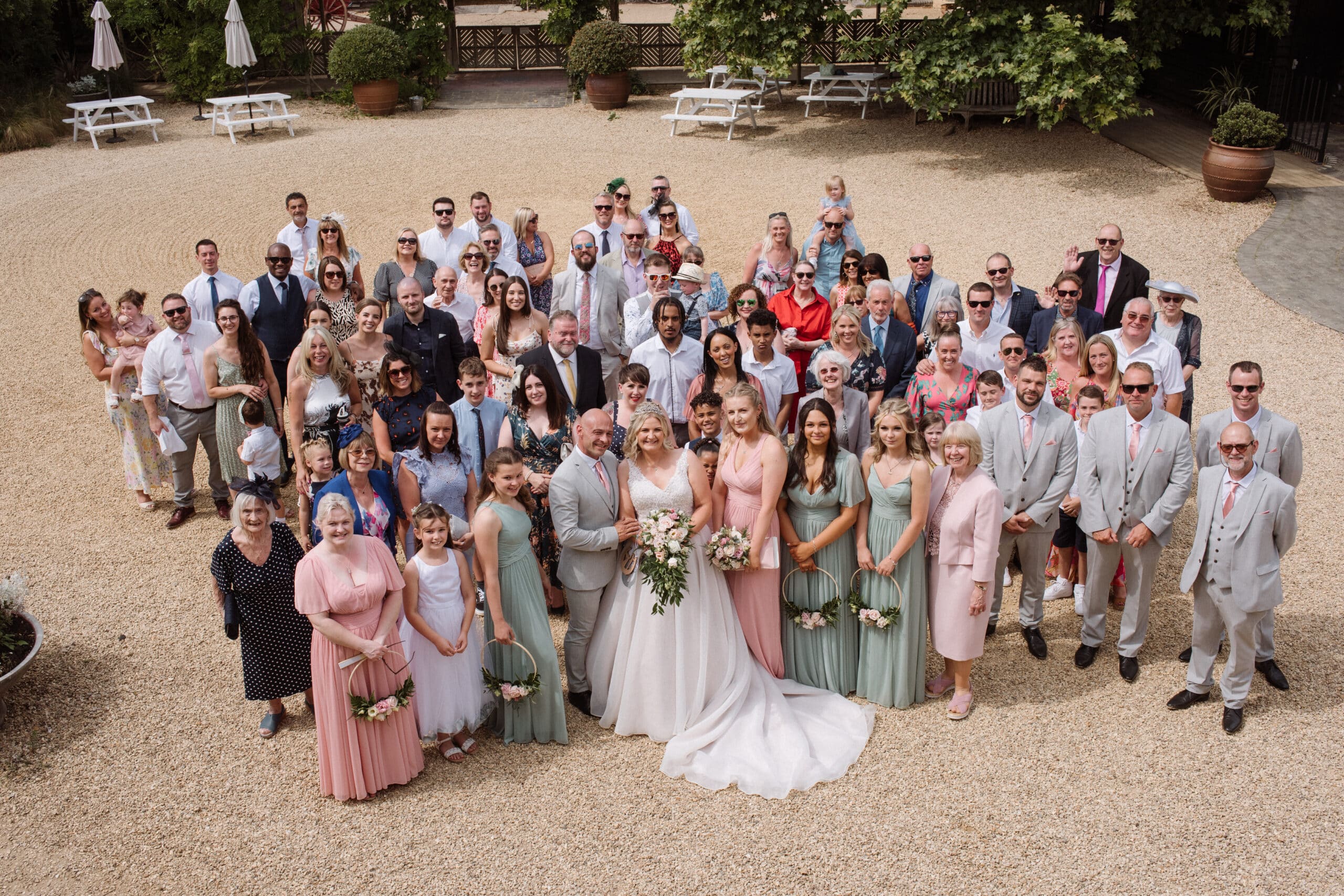 Just married bride and groom gather with their guests in a group photo in courtyard of farm wedding venue