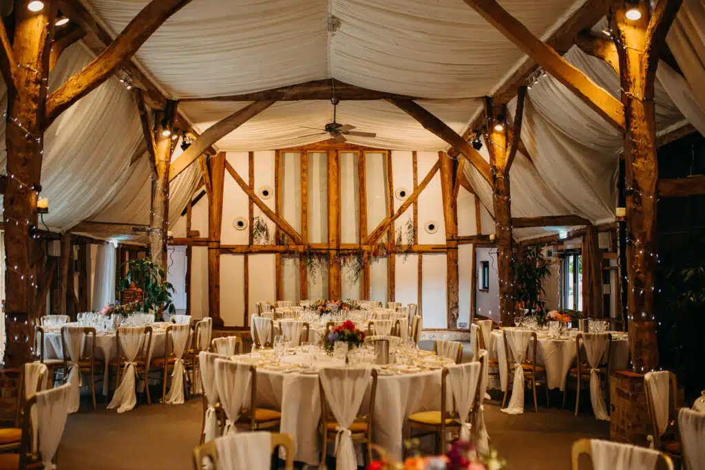 Rustic Barn Wedding Venue set for dining with white chair covers and floral decorations