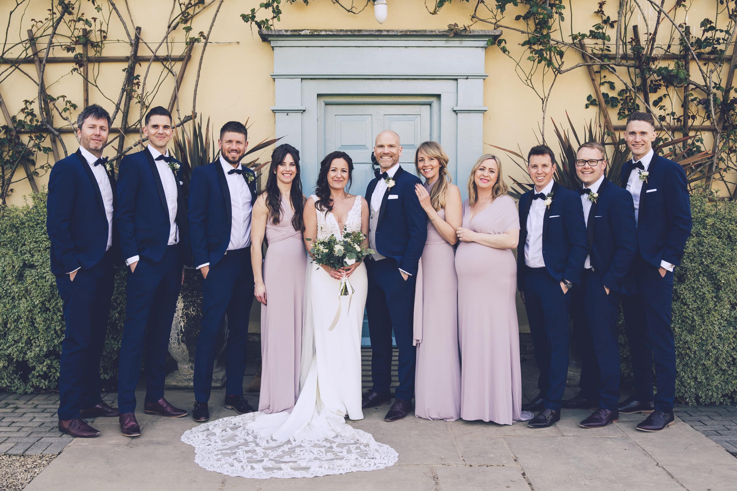 Bride and groom with bridal party on sunny day at countryside wedding venue