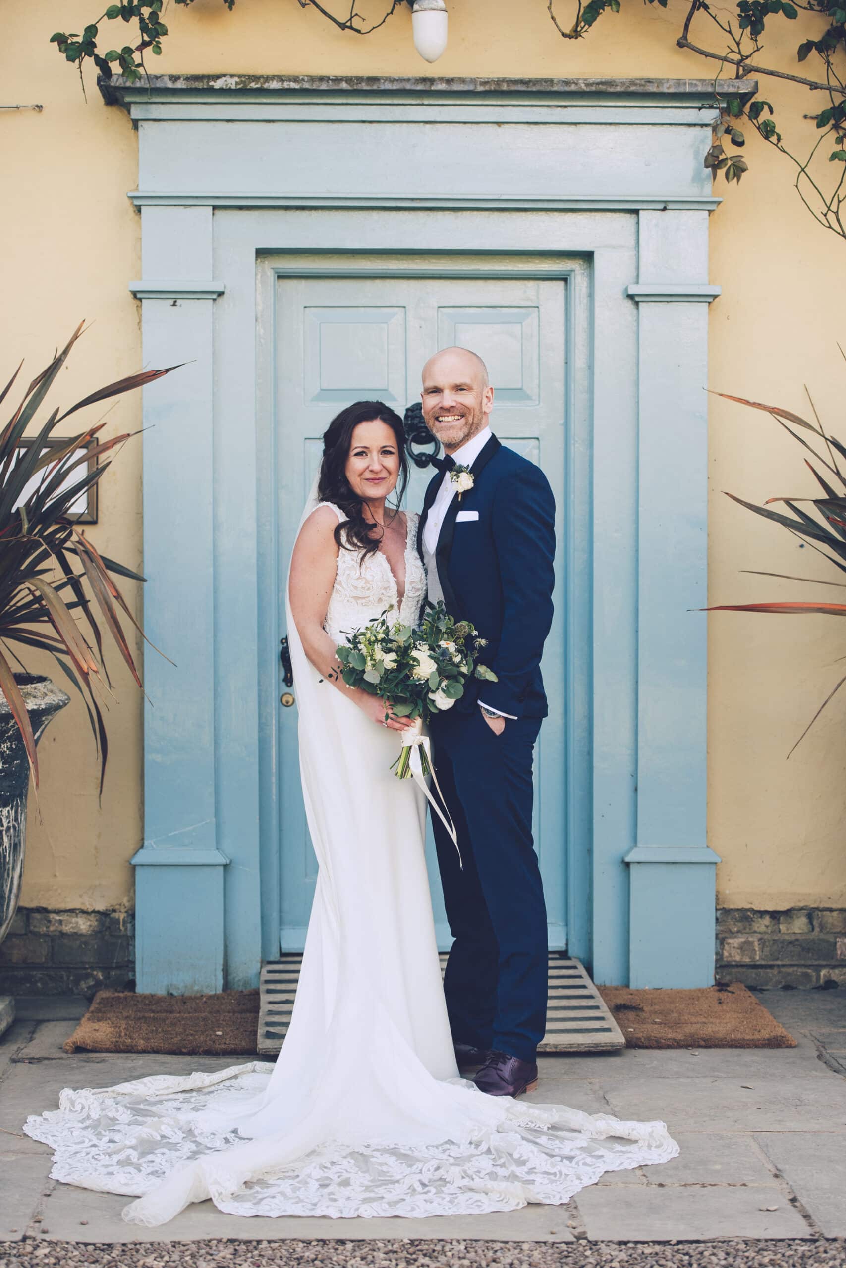 Bride and Groom at blue door of Cambridgeshire Country Farmhouse wedding venue