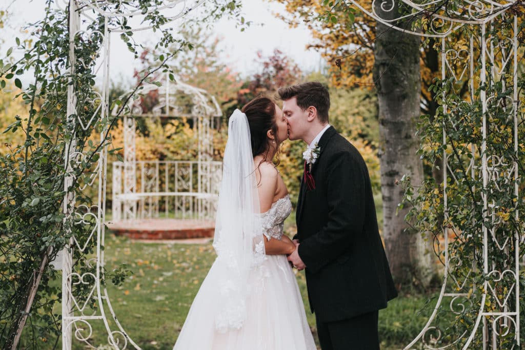 Bride and Groom kiss in romantic garden wedding venue