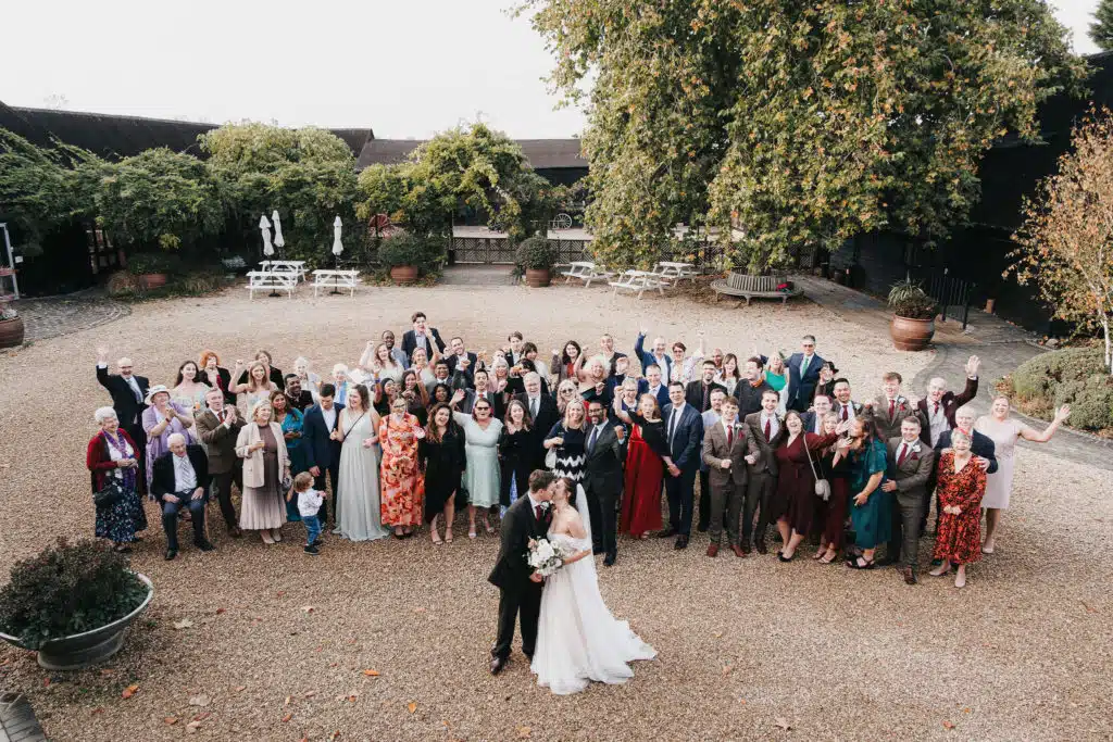 Bride and Groom on their wedding day with all their guests gathered in courtyard at farm wedding venue