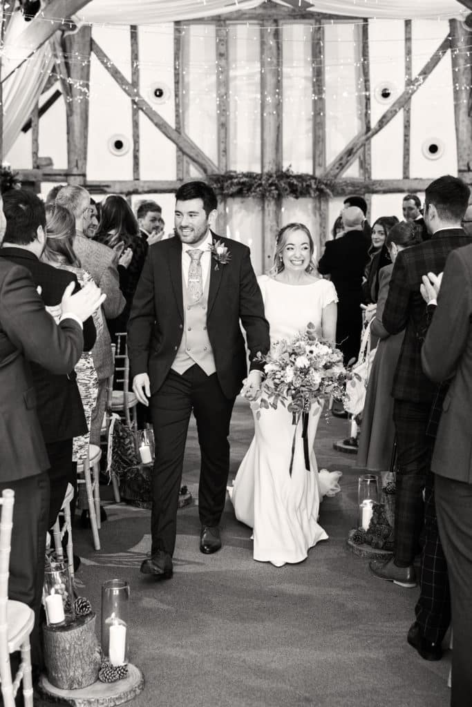Bride and Groom just married walk down aisle of barn wedding venue 