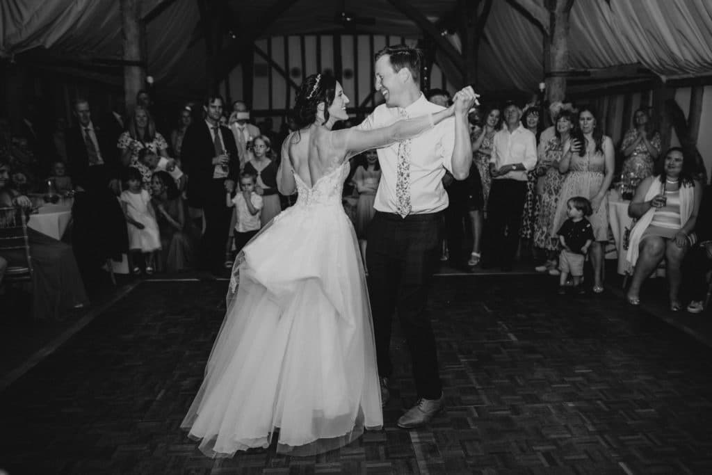 Bride and groom enjoy their first dance at barn wedding venue black and white photo