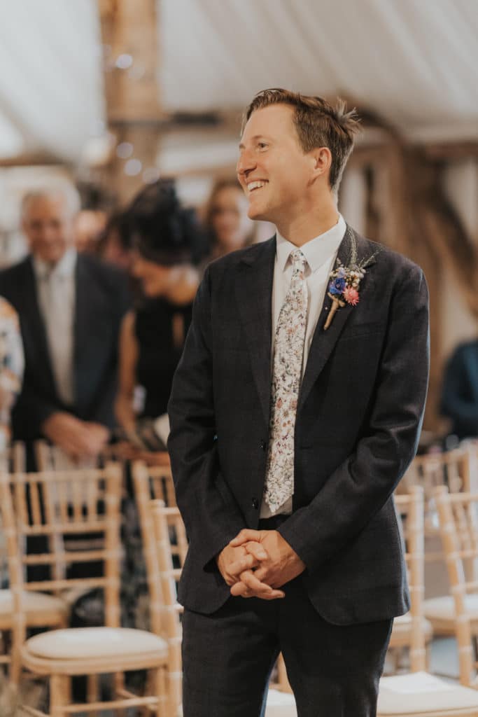 Smiling Groom waits for Bride at Barn wedding ceremony