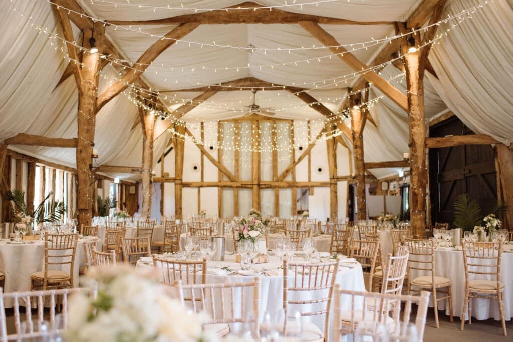 Beautiful converted barn wedding venue with twinkly fairy lights set for wedding meal