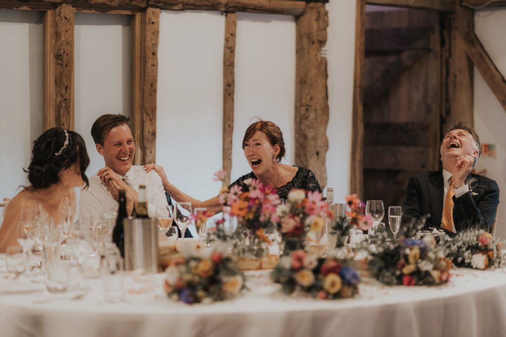Bride, groom and top table guests enjoy wedding day speeches at barn wedding venue