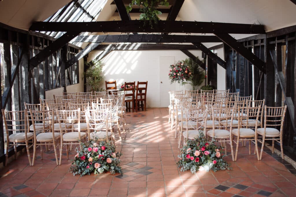 Barn Wedding set for ceremony with pretty pink flowers and black timber beams