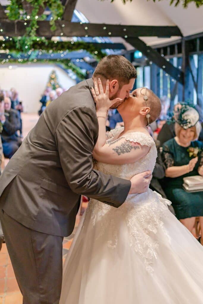 Bride and Groom kiss at rustic barn wedding ceremony