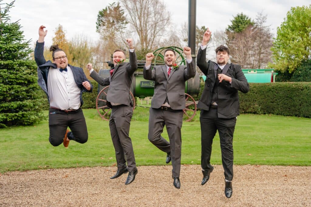 Groom and ushers jump for joy at winter wedding in front of old steam engine 