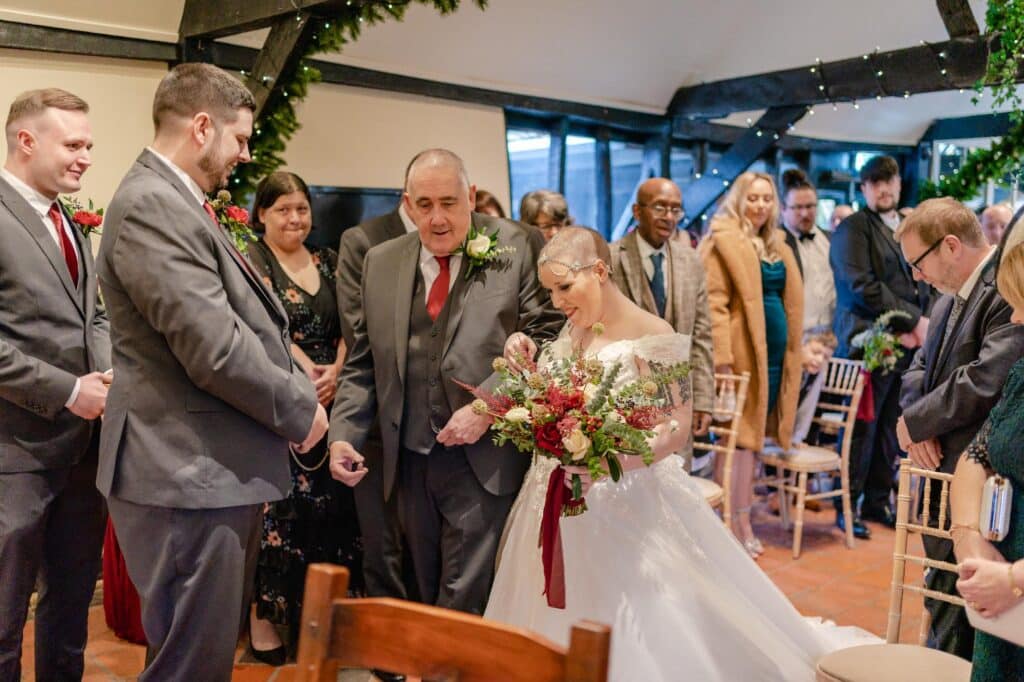 Bride walks down the aisle with father of the bride and meets groom at rustic barn wedding ceremony 