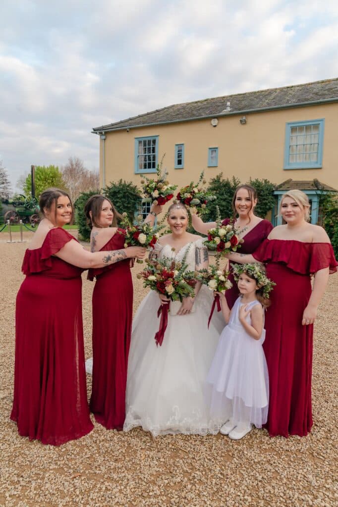 Bride and Bridesmaids on winter wedding day in front of cream country farm house 