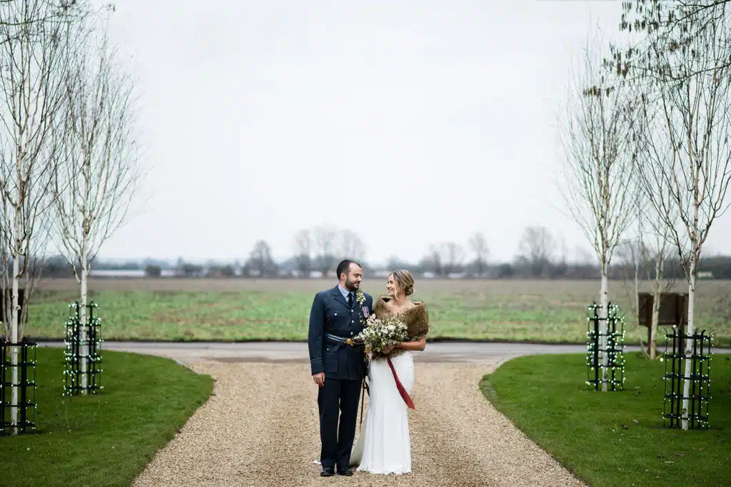 Bride and groom at end of fairy lit tree lined driveway on winter wedding day