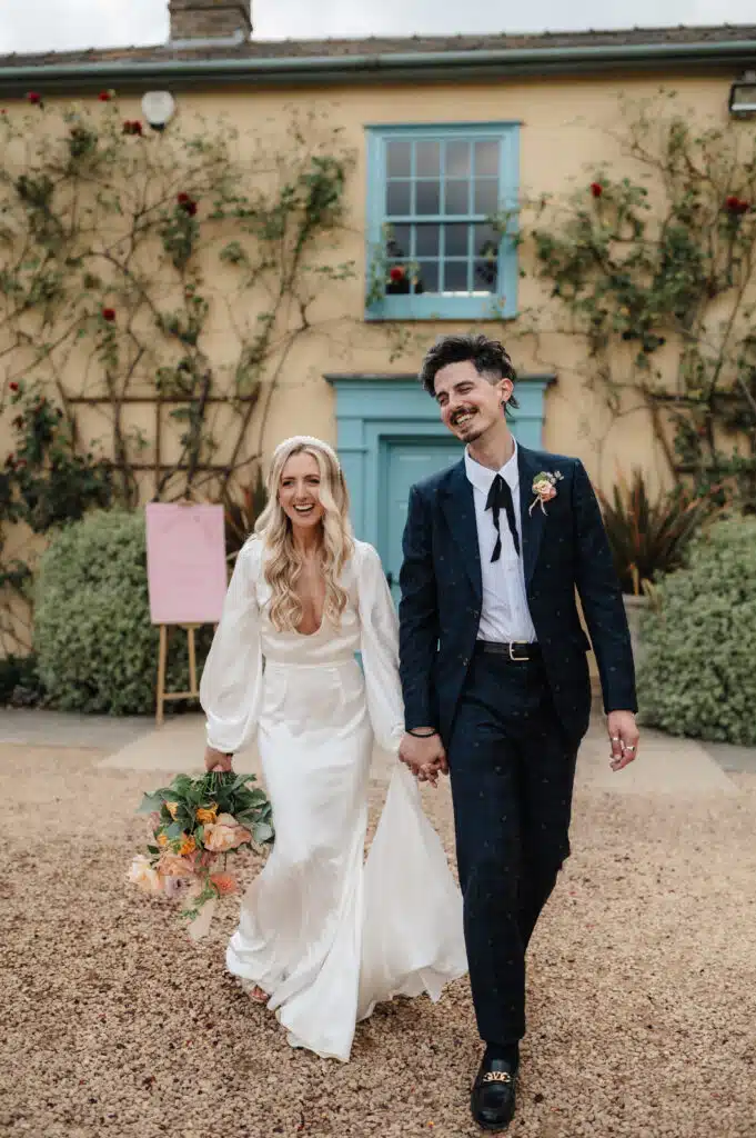 Bride and Groom hand in hand at country farmhouse wedding venue