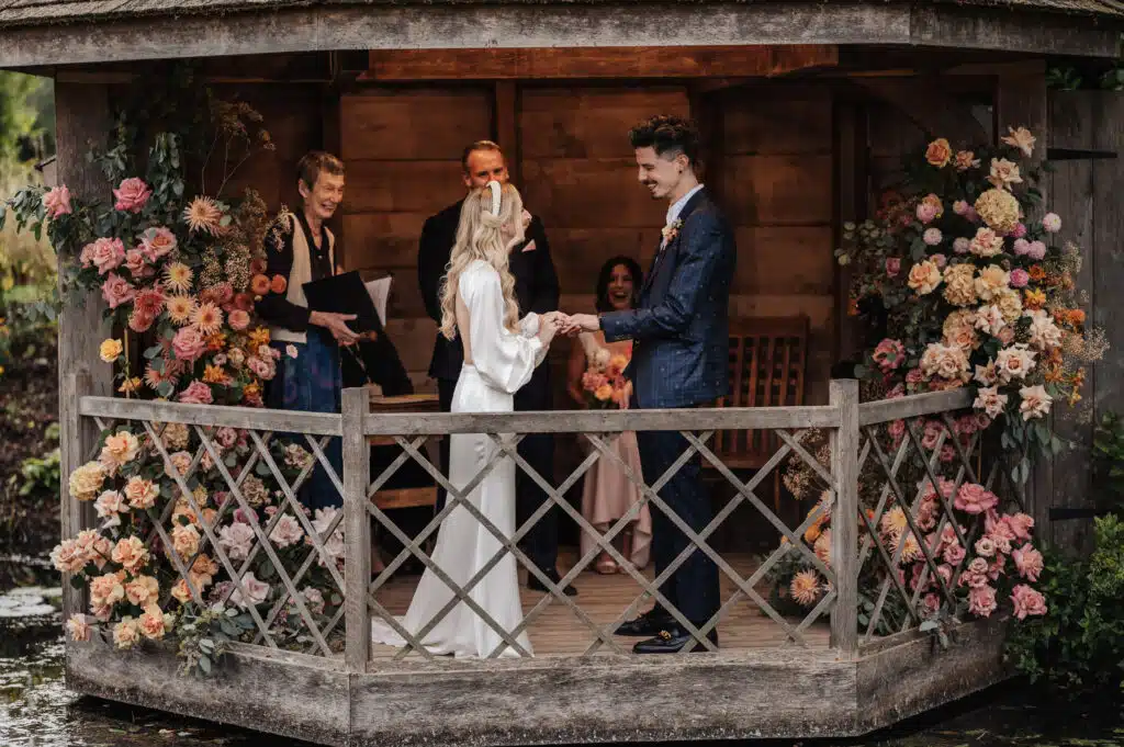 Bride and Groom exchange vows in Garden Summerhouse Wedding Ceremony surrounded by flowers