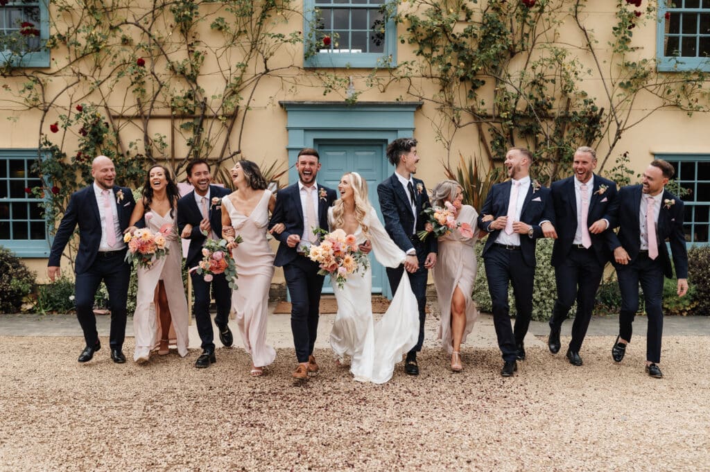 Wedding Party walk away from cream and blue country farmhouse on wedding day