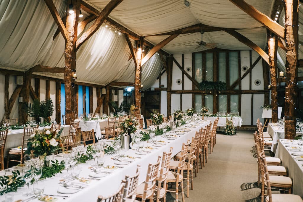 Beautiful rustic barn set for wedding meal with long tables and green table decorations