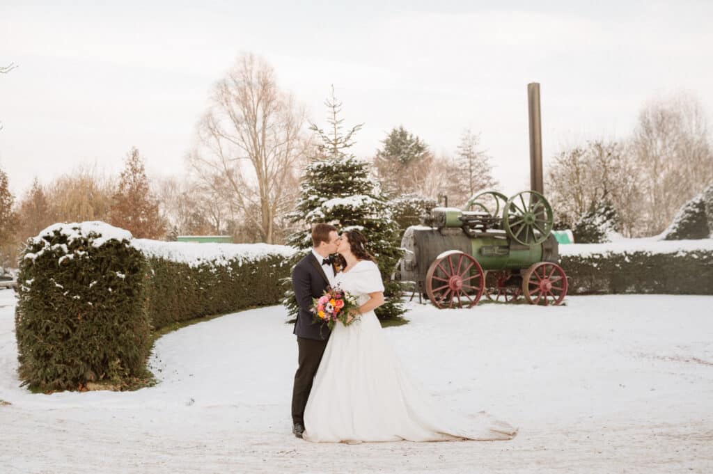 Bride and Groom at countryside winter wedding in front of vintage steam engine in the snow
