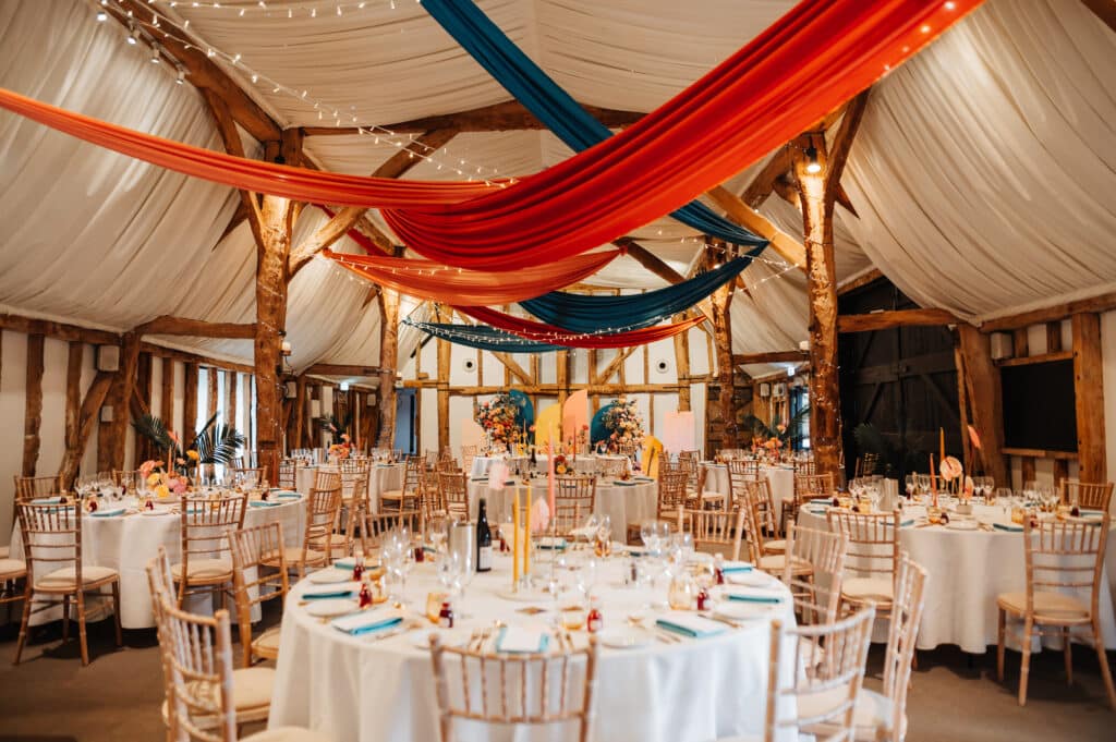 Bright colourful red and blue drapes in rustic wedding barn