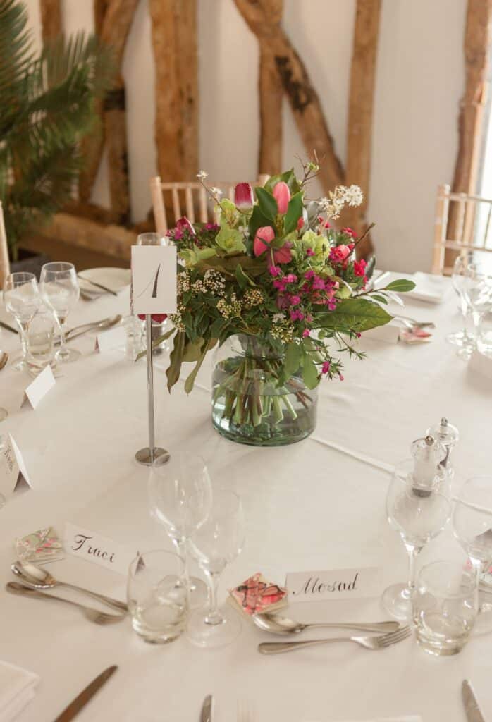Pink and green flower centrepieces at rustic barn wedding venue