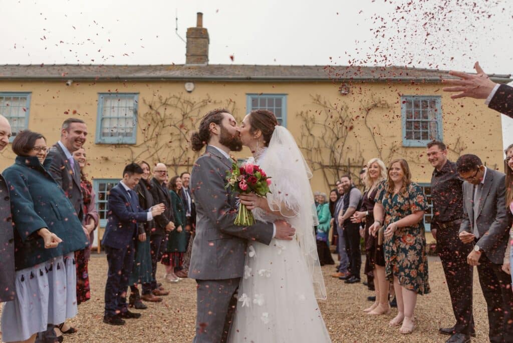 Bride and groom kiss in front of country house wedding venue