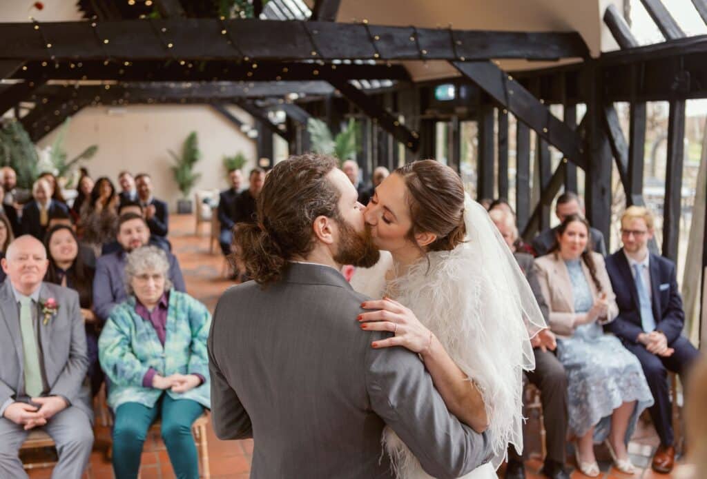 Bride and groom kiss at barn wedding ceremony