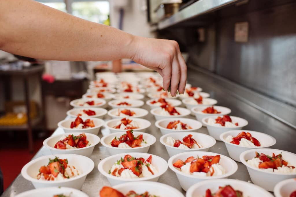 Chefs preparing strawberries and cream in catering kitchen at wedding venue 