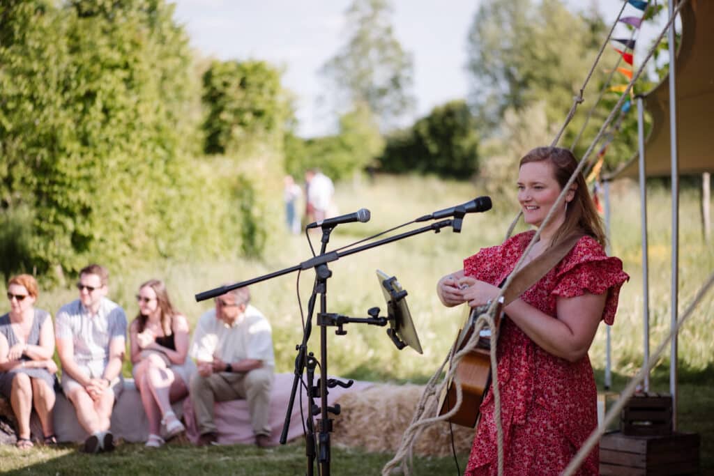 Singer in red dress on sunny afternoon at charity event garden wedding venue