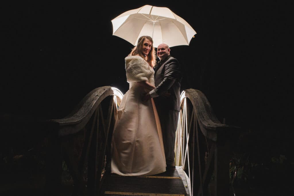 Jewish Wedding bride and groom at night on bridge with white umbrella countryside wedding venue 