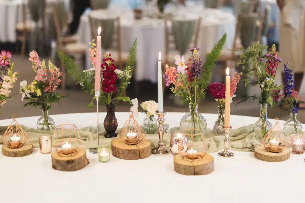 Colourful candles and flowers on rustic log rounds with pretty geometric candle holders 