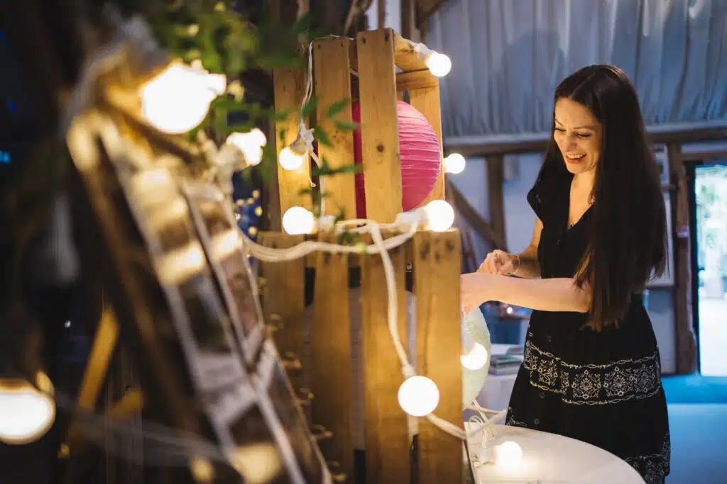 Event stylist adding finishing touches to props and display table at barn wedding venue 