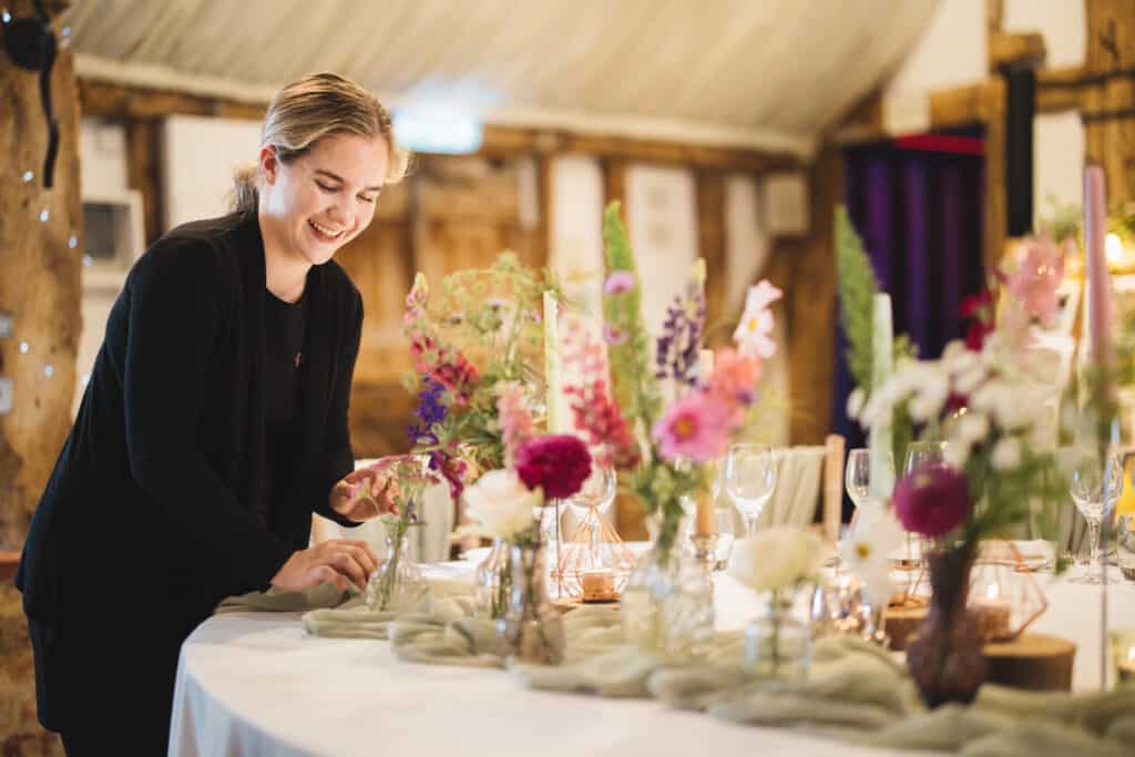 Event stylist adding finishing touches to table decor at barn wedding venue 