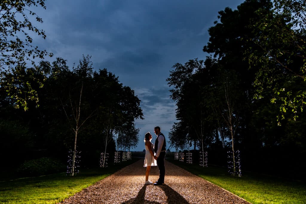 Bride and Groom on driveway lit with fairylights at nighttime countryside wedding venue