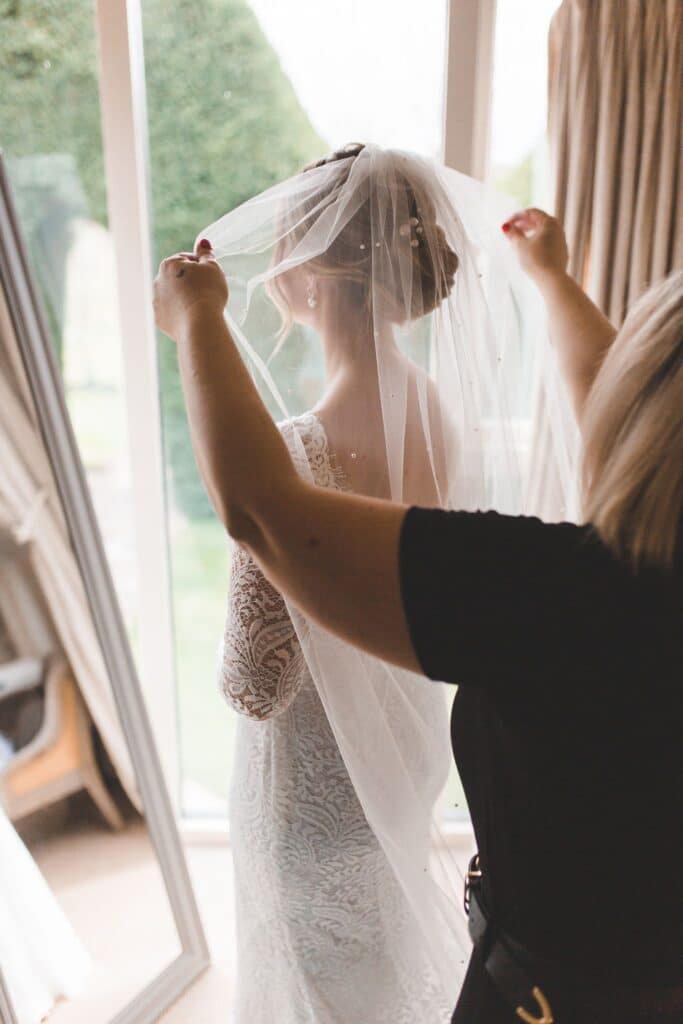 Bride helped into veil in luxury suite at countryside wedding venue